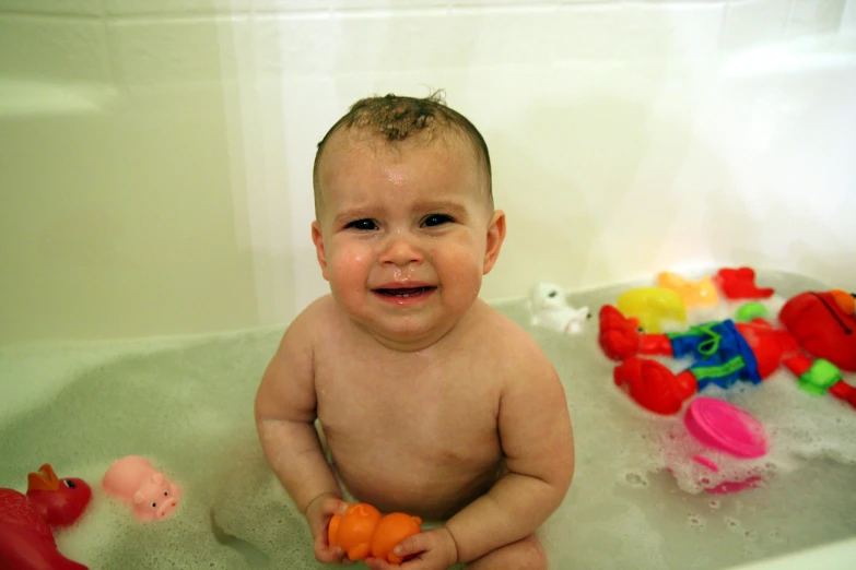 a toddler is playing in the bathtub with a rubber ducky