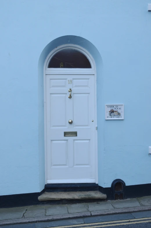 a large white door with metal details is open in front of a blue building