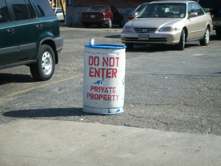 a sign next to a trash can in the parking lot