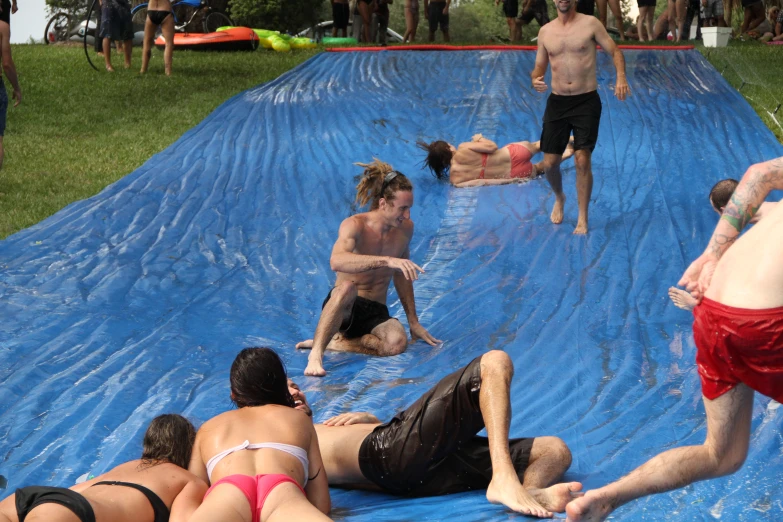 several people laying on a pool with an artificial wave board in the back