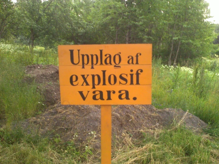 an orange sign sitting next to a pile of dirt and trees