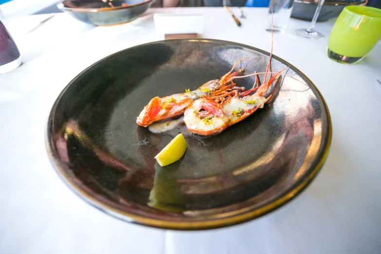 a dish of lobster with a side of lemon slice