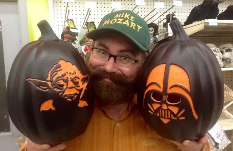 a man with three pumpkins painted with star wars logos