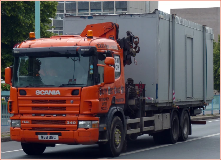 an orange truck with its flatbed trailer turned backwards