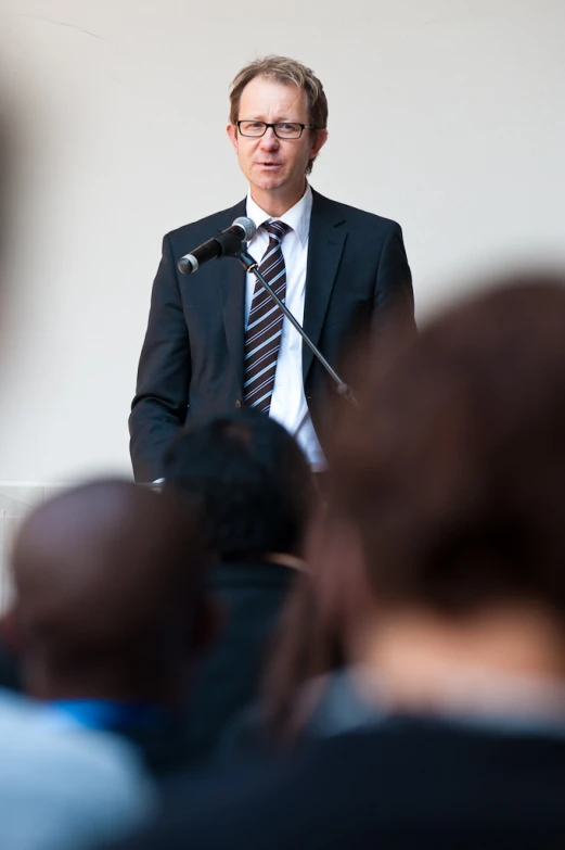 a man wearing a suit and tie standing at a podium