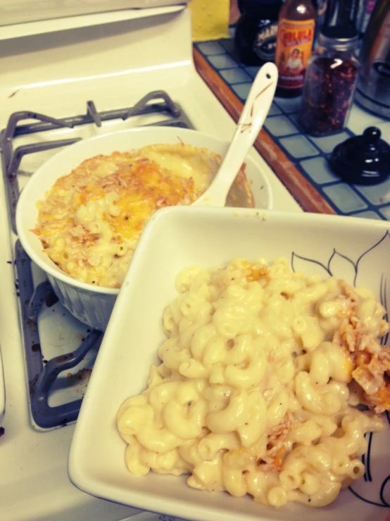 a bowl with macaroni and cheese sitting on top of a stove