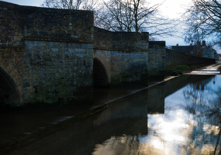 an old bridge over a small river near the town