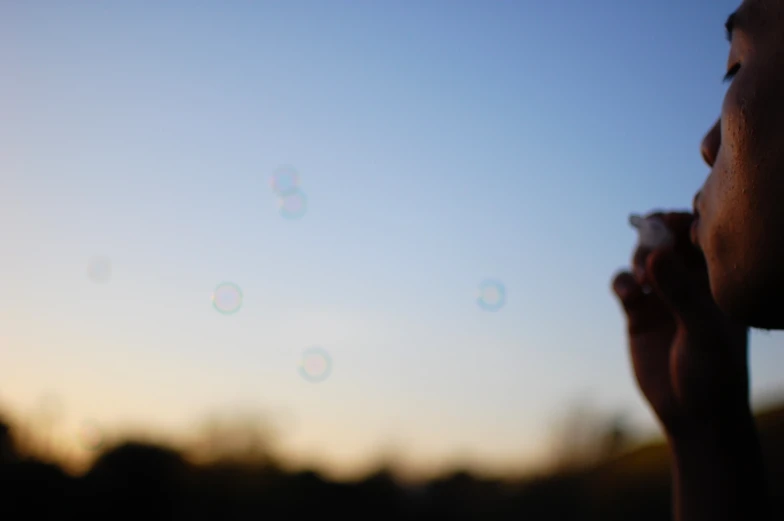 a girl is blowing bubbles in the air