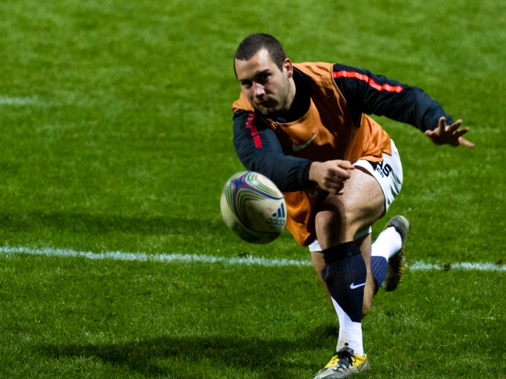 a man wearing an orange uniform catching a soccer ball