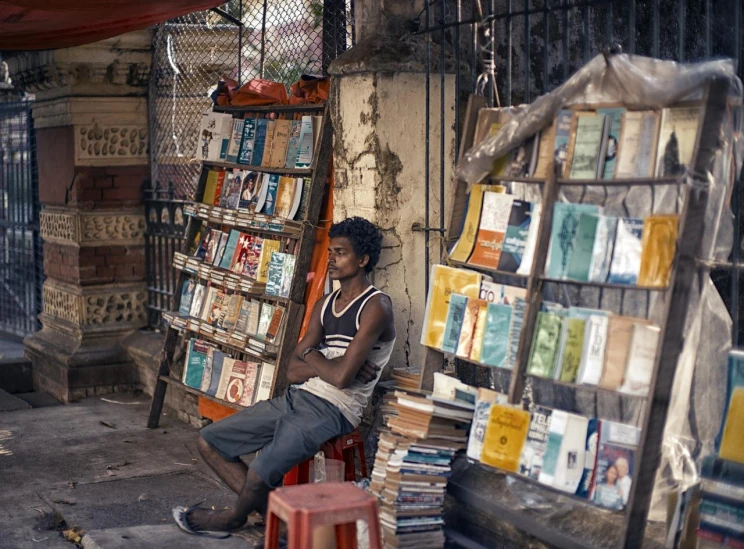 a man sitting on the ground near a lot of books