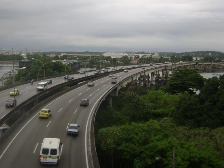 the freeway with many cars is seen near many trees