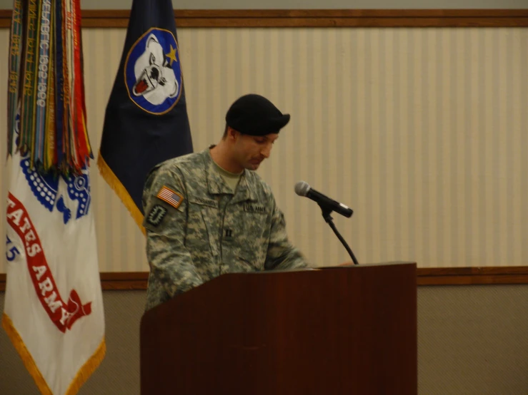 a man standing behind a podium at a podium with flags