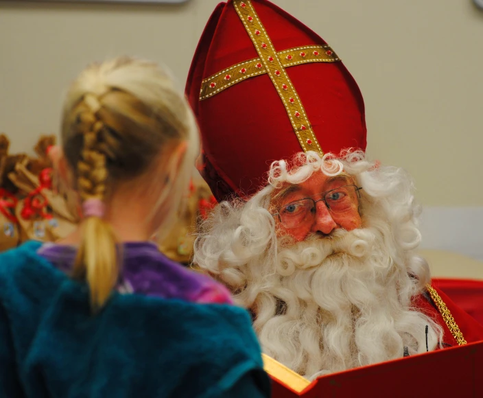 a small girl standing next to santa clause