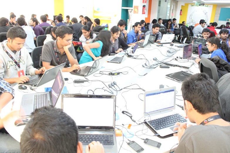 many people are gathered around a table with laptops on it