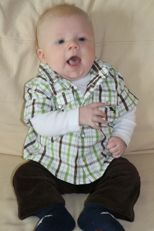 a baby with a striped shirt sits on a brown blanket