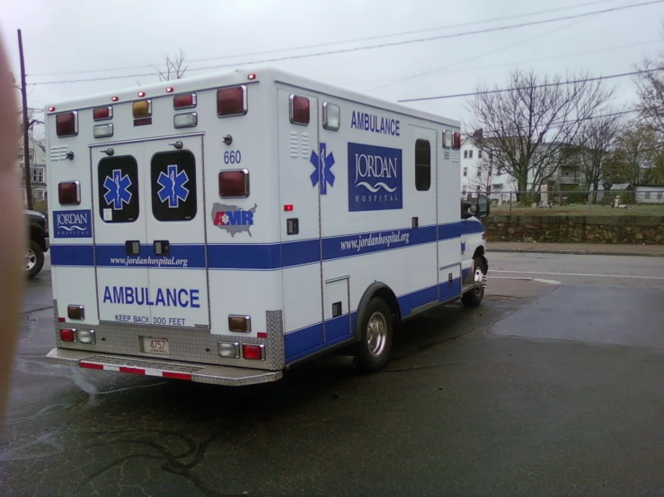 an ambulance sits in a parking lot with emergency signs on it