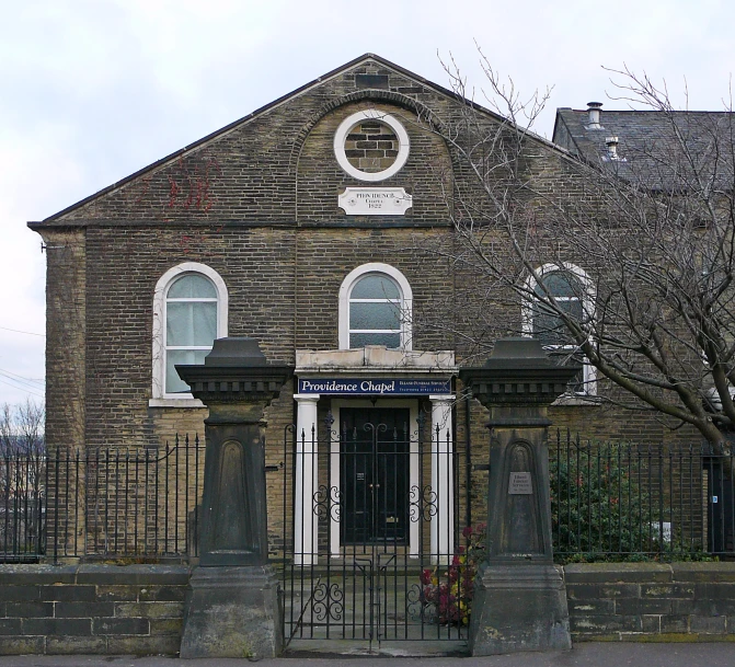 an old brick building with a gate at the front