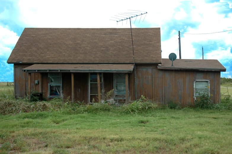 a brown shed and a red car parked in a field