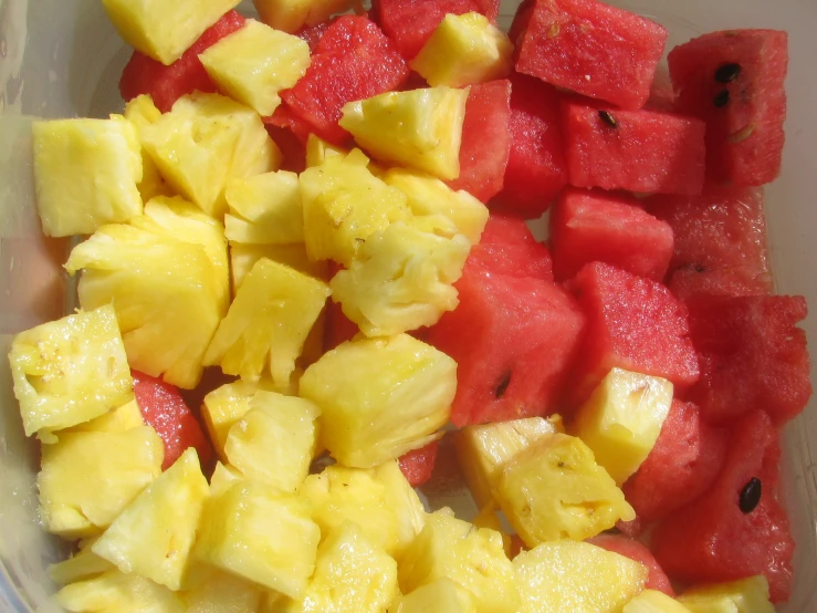 a bowl filled with cut up melon and pineapple