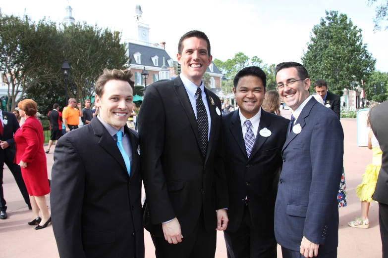 four men standing next to each other in front of a building