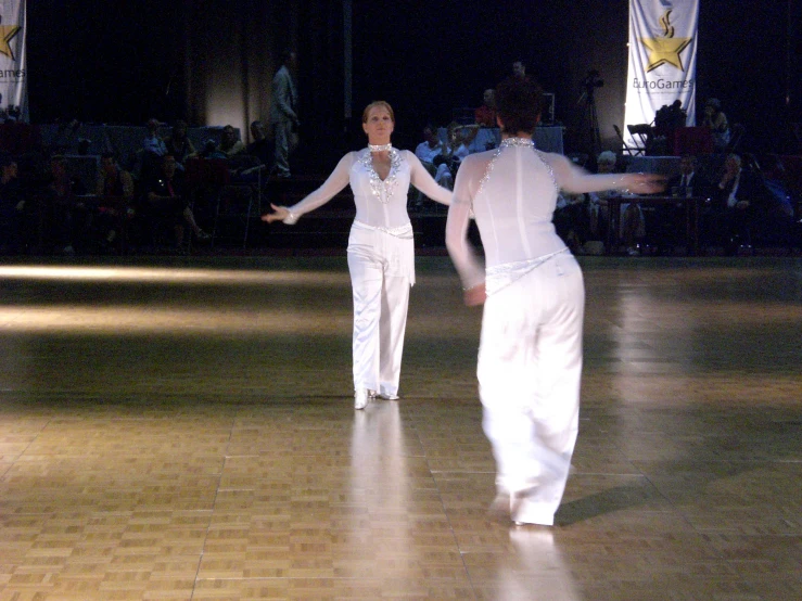 two ladies wearing white dancing on the dance floor