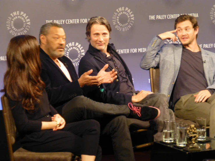 the three actors are having a conversation in front of a panel