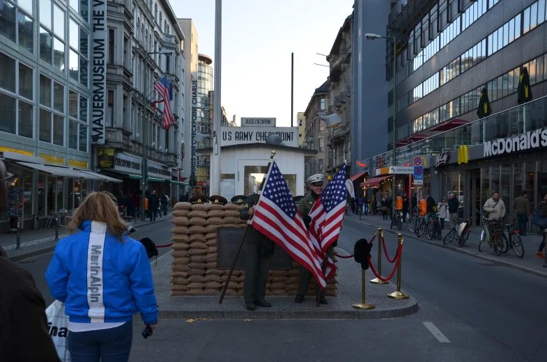 two flags being held up on the side of a street