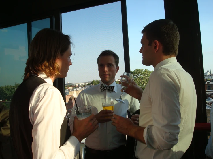 three men standing talking while drinking drinks at a party