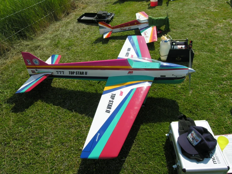 an airplane painted with multi - colored stripes sits in a field