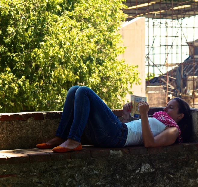 a woman laying down on some concrete and reading