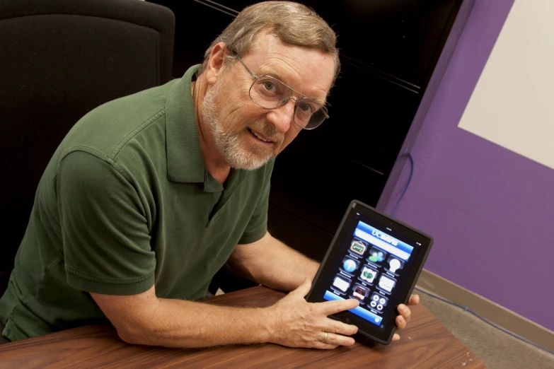 a man wearing glasses holding a tablet and smiling