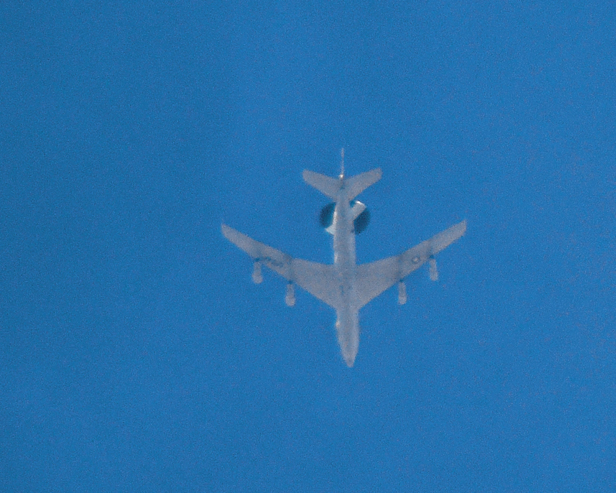 an airplane flies overhead with a blue sky behind it