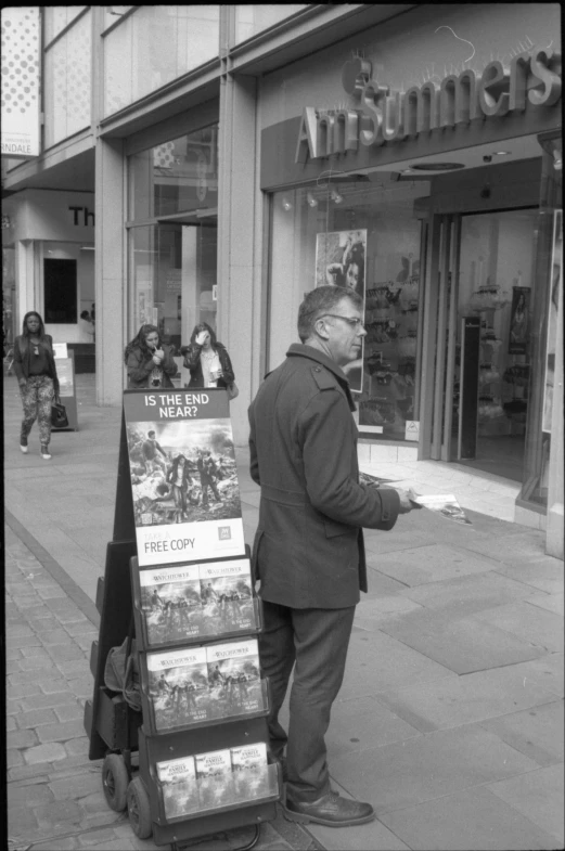 a black and white po of man leaning on a book stand