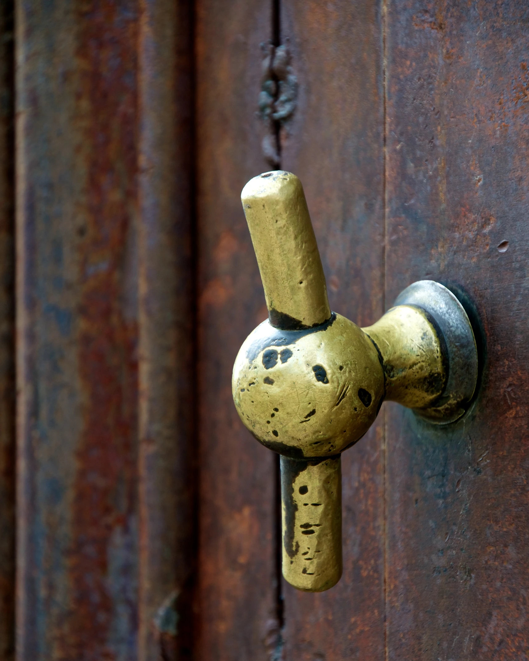 a golden door handle with rusted paint
