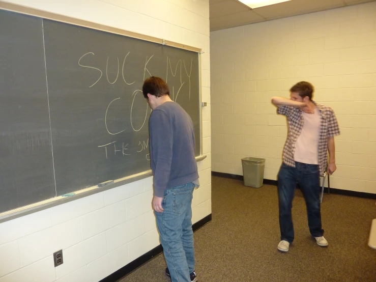 two students writing on a chalkboard with their hands