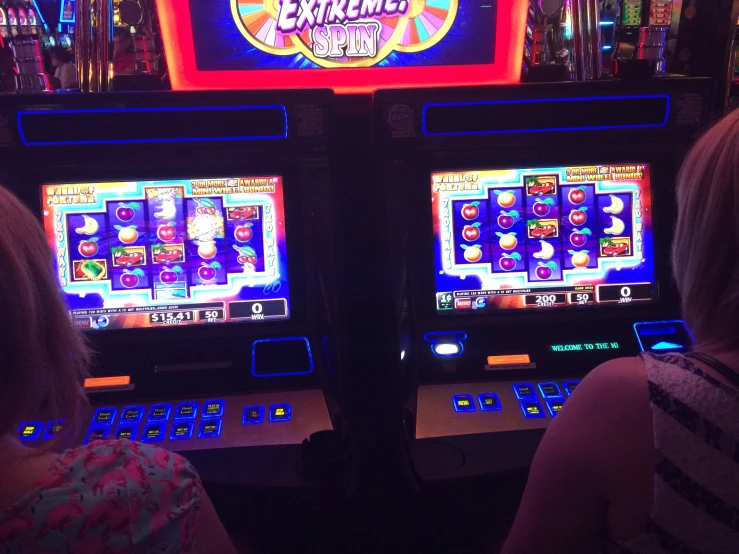 two girls are playing slot machines inside the casino