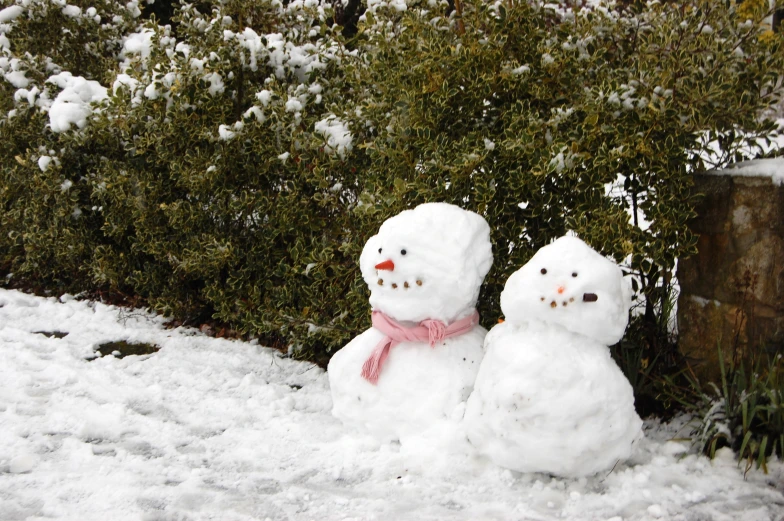 two snowmen standing in the snow outside