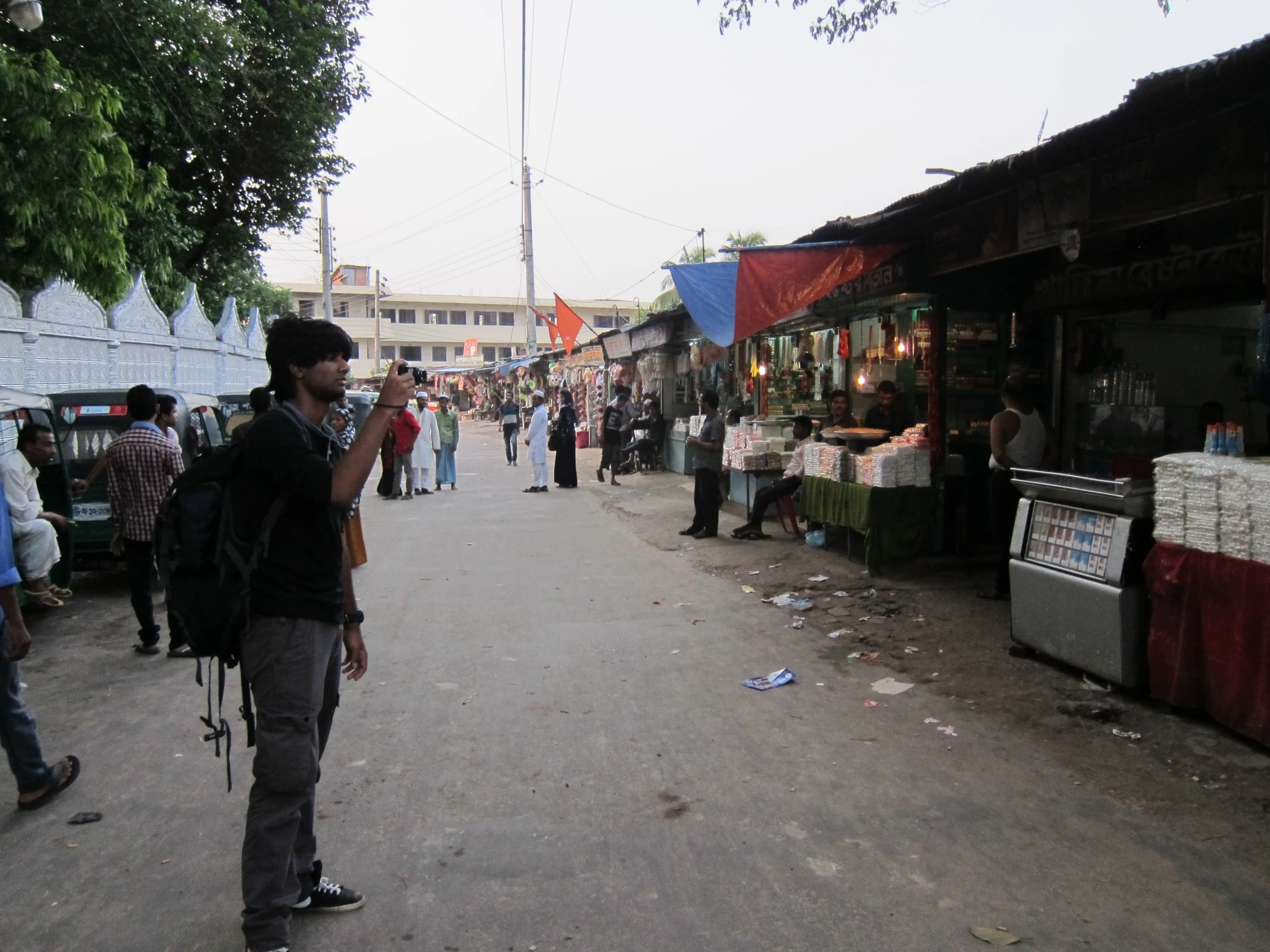 a man in a black backpack walks down a street