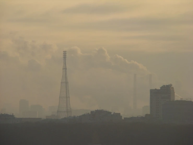 a smokestack in the distance as seen from a far away field