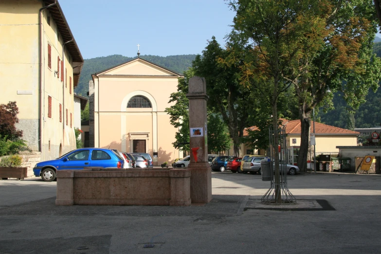 blue car on road next to buildings with trees