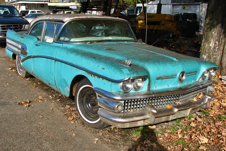 a blue classic car sitting next to a tree