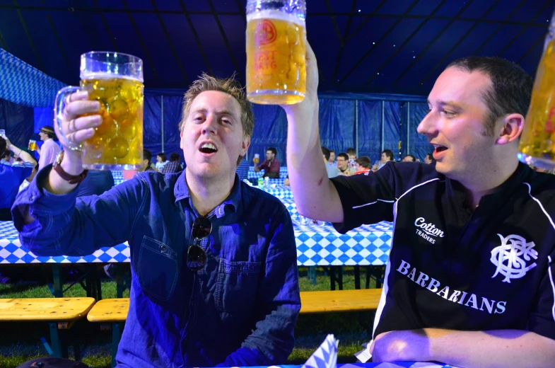 two people are drinking beers together at a bar