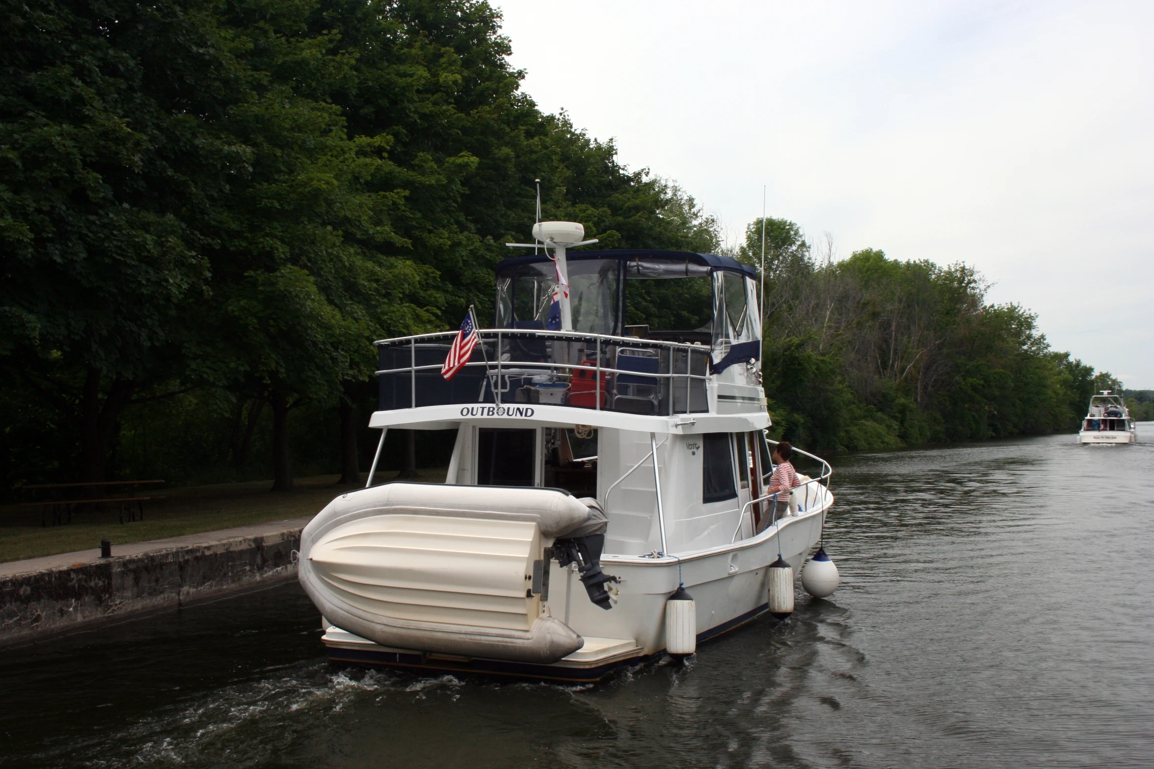 white boats floating down a river next to some trees