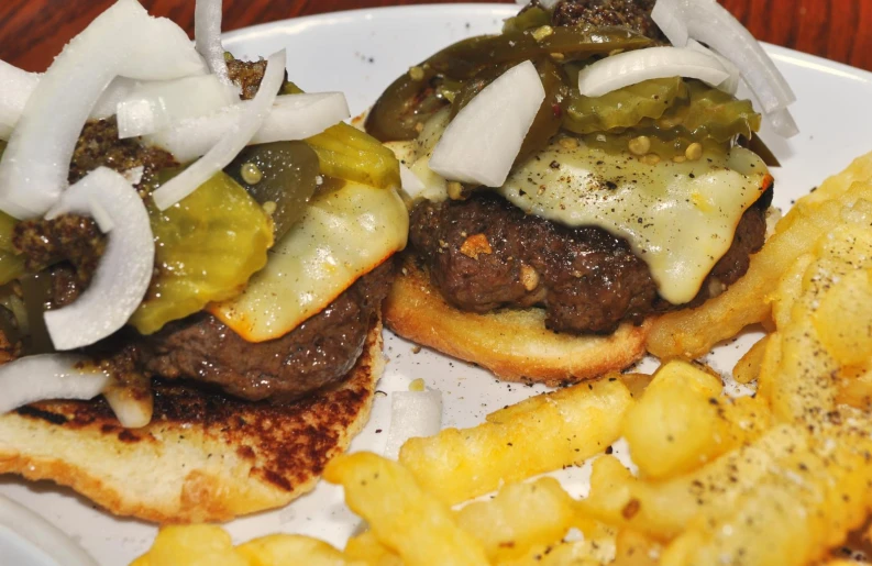 the beef burger on a plate is topped with sauce, cheese and onions