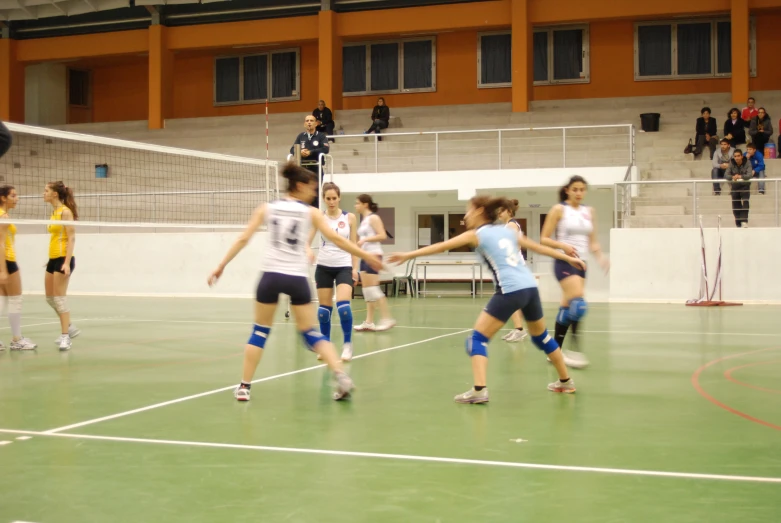 some women are playing volley ball on an indoor court