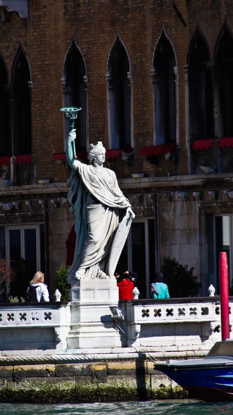 a statue with a torch near a body of water