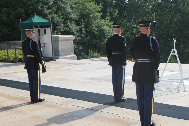 three men in service uniforms stand next to each other