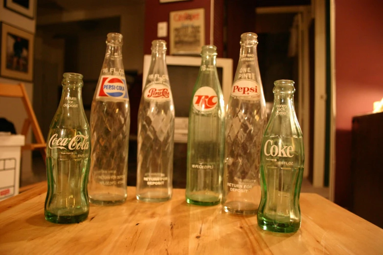 several coca - cola bottles of different kinds and sizes lined up on a table