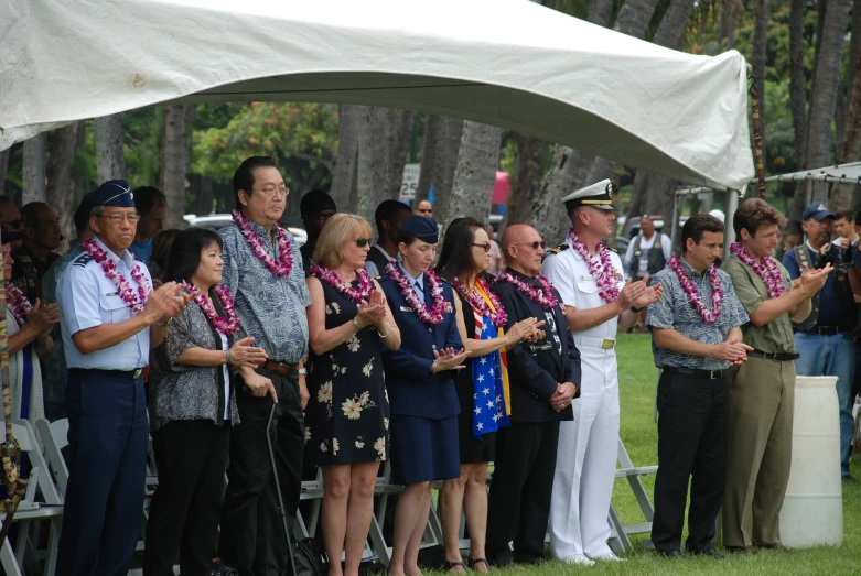 people in uniforms stand under a white tent