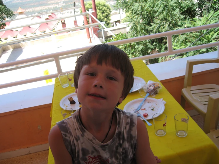 a boy is smiling in front of a yellow tablecloth